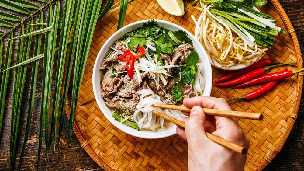 Pho Bo vietnamese Soup with beef and chopsticks in male hand